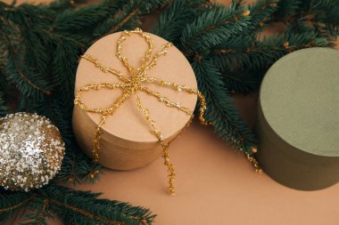 Noel, şenlikli bir geçmiş. Kahverengi ve yeşil hediye kutuları kahverengi arka planda yeşil kozalaklı dalların üzerinde goolden ribon. Üst görünüm