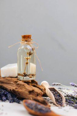 Açık arkaplanda lavanta yağı ve parlak güneş ışığı altında lavanta çiçekleri. Ön görünüm