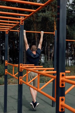 Açık hava sporları. Yaz sabahı spor sahasında egzersiz yapan bir adam. Sağlıklı yaşam tarzı kavramı. Ön görünüm