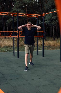 Açık hava sporları. Yaz sabahı spor sahasında egzersiz yapan bir adam. Sağlıklı yaşam tarzı kavramı. Ön görünüm