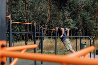 Açık hava sporları. Yaz sabahı spor sahasında egzersiz yapan bir adam. Sağlıklı yaşam tarzı kavramı. Ön görünüm