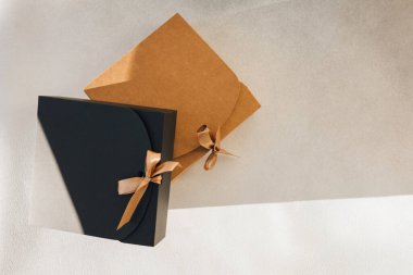 Selamlama arka planı. Gri arka planda kahverengi ve siyah hediye kutuları ve fotokopi alanı. Üst görünüm