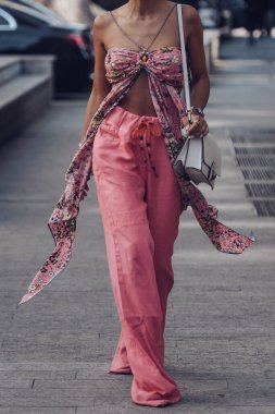 Milan, Italy - February 25, 2022: Woman in stylish pink pants and ornamental crop top with white bag in Milan.