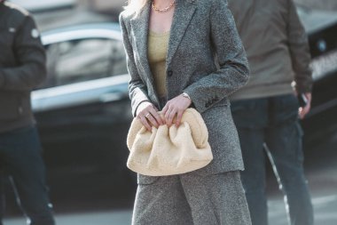 Milan, Italy - February 25, 2022: Female in stylish gray suit with yellow lime top with bag in Milan, Italy.