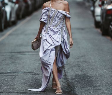 Milan, Italy - February 25, 2022: Anonymous woman in fancy dress and sandals with handbag in Milan, Italy.
