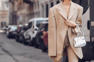 Milan, Italy - February 26, 2022: Woman in stylish beige suit adjusting jacket.