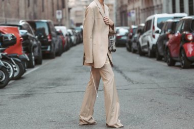 Milan, Italy - February 26, 2022: Woman in stylish beige suit adjusting jacket.