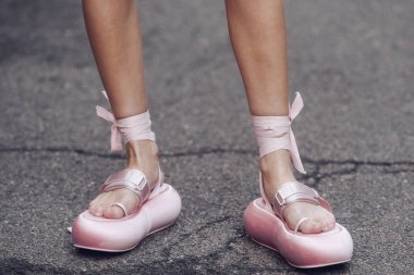 Milan, Italy - February 25, 2022: Anonymous female in stylish pink sandals with ribbons tied around ankles standing in Milan.