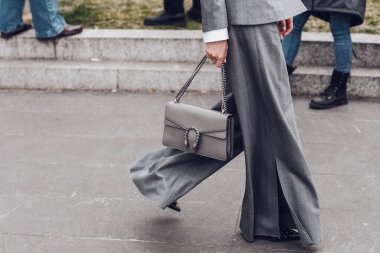 Milan, Italy - February 24, 2022: Woman in gray jacket and wide leg pants with chain purse.