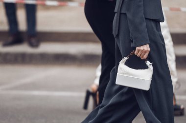 Crop fashionable woman walking on street with handbag
