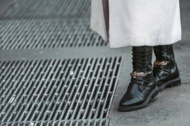 Milan, Italy - February 24, 2022: Woman wearing trendy beige coat and black leather boots with laces.
