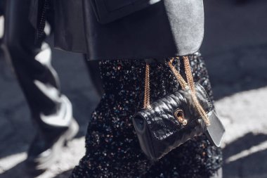 Milan, Italy - February 26, 2022: Female wearing a black glitter dress and black purse white golden lace.