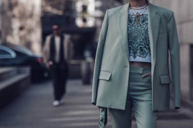 Milan, Italy - February 25, 2022: Female wearing a light green blazer, ornamental shirt and matching ornamental handbag.