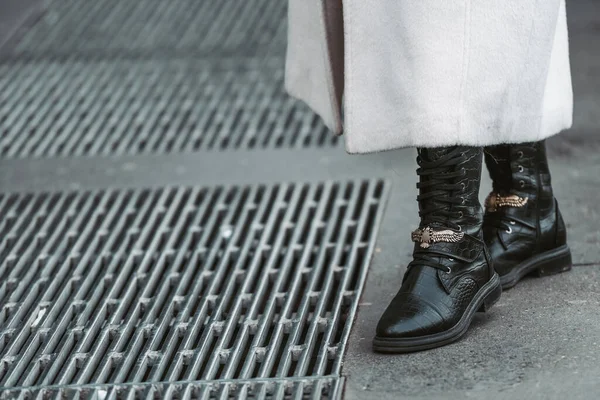 Milan, Italy - February 24, 2022: Woman wearing trendy beige coat and black leather boots with laces.