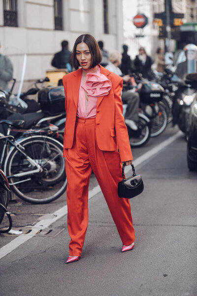 Milan, Italy - February 25, 2022: Female wearing a red fancy suit, black handbag and pink elegant shoes.