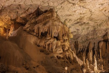 Postojna mağarasının tavanından sarkan pek çok narin sarkıt. Beyaz noktalar su damlacıklarındaki ışığı yansıtır.