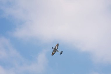 Editör: DEURNE, FLANDERS, BELGIUM, 21 Mayıs 2023 - Supermarine Spitfire, Antwerp Havalimanı 'nın 100. yıldönümünde hava gösterisi sırasında siyah ve beyaz istila çizgileri ile üstümüzden geçiyor