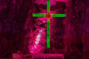 Mağarada yanan bir haç ve bir bank.