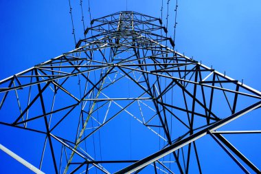 Çelik elektrik direği ve yüksek voltajlı elektrik hattı mavi gökyüzü arkaplanlı elektrik iletim fotoğrafı.