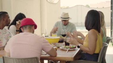 Arkadaşlarıyla yemek yiyen şapkalı Latin bir adamın 4K videosu. Yüksek kalite 4k görüntü