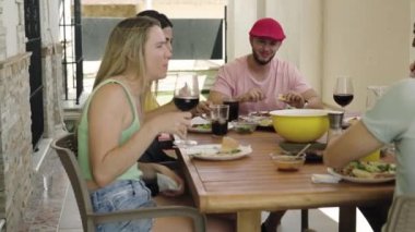 4K videosunda kırmızı şapkalı bir adam arkadaşlarıyla konuşurken daha fazla arkadaşıyla yemek yiyor. Yüksek kalite 4k görüntü