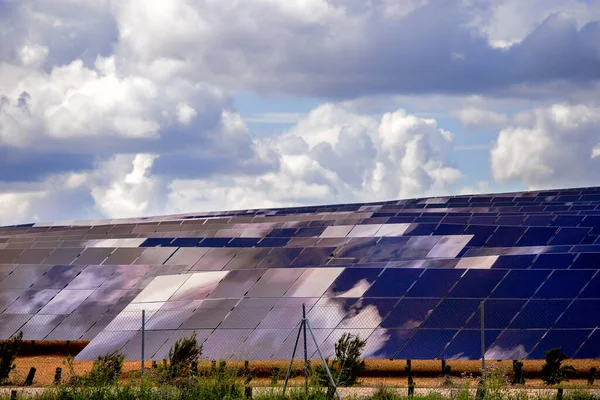 Silicon panels of solar batteries against the cloudy sky in the middle of the day.
