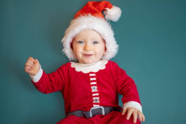 Yeşil arka planda Noel Baba kostümlü küçük şirin bebek portresi..