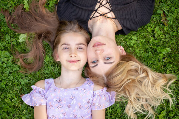 Mother and daughter lying on green grass.