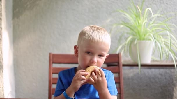 Kleiner Junge Isst Einen Donut Während Hause Tisch Sitzt — Stockvideo