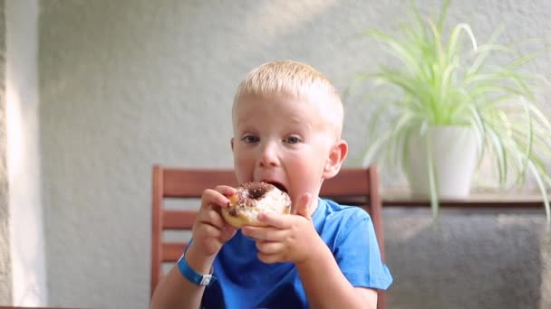 Menino Comendo Donut Enquanto Sentado Uma Mesa Casa — Vídeo de Stock