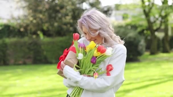 Mujer Sonriente Oliendo Flores Tulipán Sobre Fondo Verde — Vídeo de stock