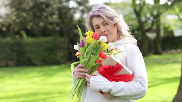 快乐的微笑的女人为礼物和郁金香花束而高兴 — 图库视频影像