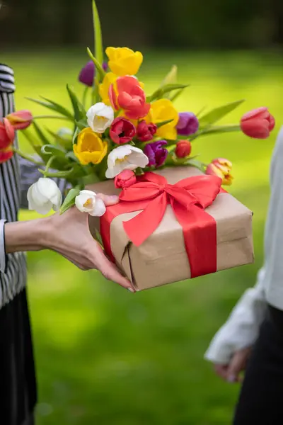 Hands Holding Gift Red Ribbon Tulips — Stock Photo, Image
