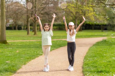 Parkta badminton raketleriyle poz veren iki kız..