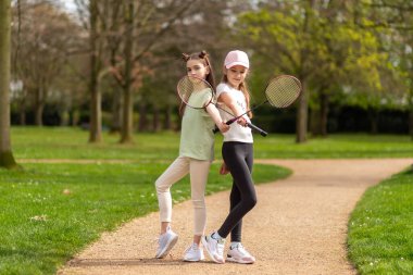 Parkta badminton raketleriyle poz veren iki kız..