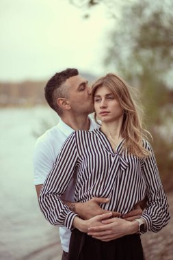 Nehrin kenarında dikilen bir çift, sarılan bir adam.