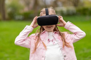 Küçük kız parkta sanal gerçeklikle etkileşime geçiyor..