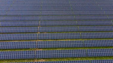 Yeşil zemin üzerindeki güneş paneli satırlarının doğrudan hava görüntüsü.