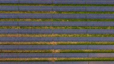 Bir alan üzerinde sıralanmış güneş panellerinin hava görüntüsü.