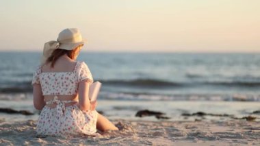 Genç bir kadın gün batımında kumlu sahilde dinleniyor, kitabına dalmış. Nazik dalgalar, güneş arkasından batarken rahatlatıcı bir ses çıkarıyor..