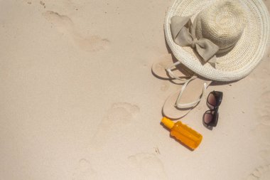 Sahil kenarında geniş kenarlı bir güneş şapkası, modaya uygun sandaletler, şık güneş gözlükleri ve sıcak, kumlu kıyılarda sergilenen güneş kremi şişesi bulunur. Rahatlamak için mükemmel..