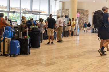 Punta Cana, Dominik Cumhuriyeti - Mart 27, 2025: Seyahatleri için bavul ve teçhizat ile hareket ederken, diğerleri kontrol etmek için kuyrukta bekleyen kalabalık havaalanı terminali kalabalık.