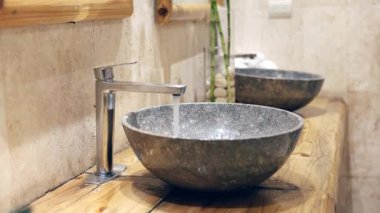Güzel işlenmiş taş bir lavabo, çağdaş bir banyoda zarif bir musluğu tamamlar. Doğal dokular uzayın genel atmosferini arttırır.
