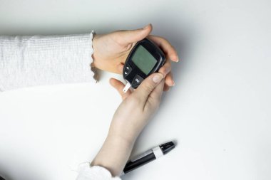 Glikoz ölçer tutan bir kişi, kapalı alanda iyi aydınlatılmış bir ortamda kan şekeri seviyelerini ölçmeye hazırlanıyor. Konferansta sağlık yönetimi ve diyabet bakımı ele alınıyor.