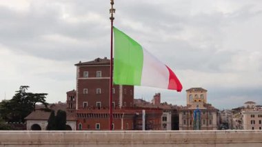 Geleneksel Roma mimarisine karşı rüzgarlı bir günde İtalyan bayrağı sallanıyor.