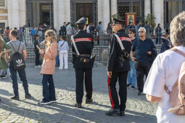 Rom, Italien - 22 Nisan 2025: Yerel kolluk kuvvetleri, güneşli bir günde Roma 'nın önde gelen tarihi bir meydanını keşfeden canlı ziyaretçiler ve turistler arasında nöbet tutuyor. Varlıkları güvenlik ve güvenliği sağlar..