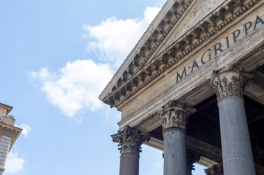 Ziyaretçiler, Pantheon 'un görkemli heybetine hayran kalarak, yüksek sütunlarını ve ayrıntılı oymalarını sergiliyorlar. Görkemli bina, canlı bir gökyüzüne karşı gururla duruyor..