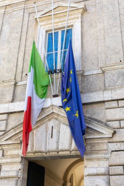 Biri İtalya 'yı, diğeri Avrupa Birliği' ni temsil eden iki bayrak Roma 'daki tarihi bir yapının girişini süslüyor ve bu güzel şehirde kültür ve yönetim karışımını gözler önüne seriyor..