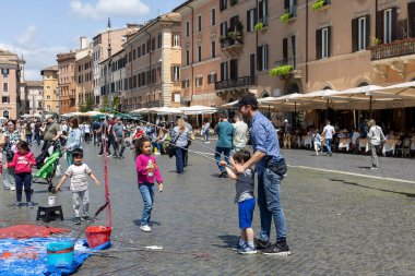 IRom, Italien - Nisan 23, 2025: hareketli meydanda, çocuklar neşeli resim faaliyetlerine girişiyor, parlak renklerle şaheserler yaratıyor, yetişkinler sohbet ediyor ve onları çevreleyen canlı atmosferin keyfini çıkarıyorlar..