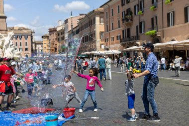 Rom, Italien - Nisan 23, 2025: Roma 'da her yaştan çocuklar, şehrin kalbinde anılar yaratarak sıcak, güneşli atmosferin tadını çıkarırken dev kabarcıklar yaratmaktan zevk alırlar..